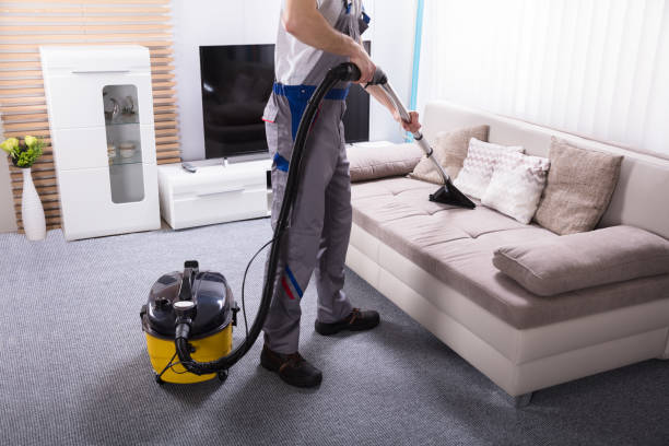 man cleaning sofa in the living room using vacuum cleaner at home